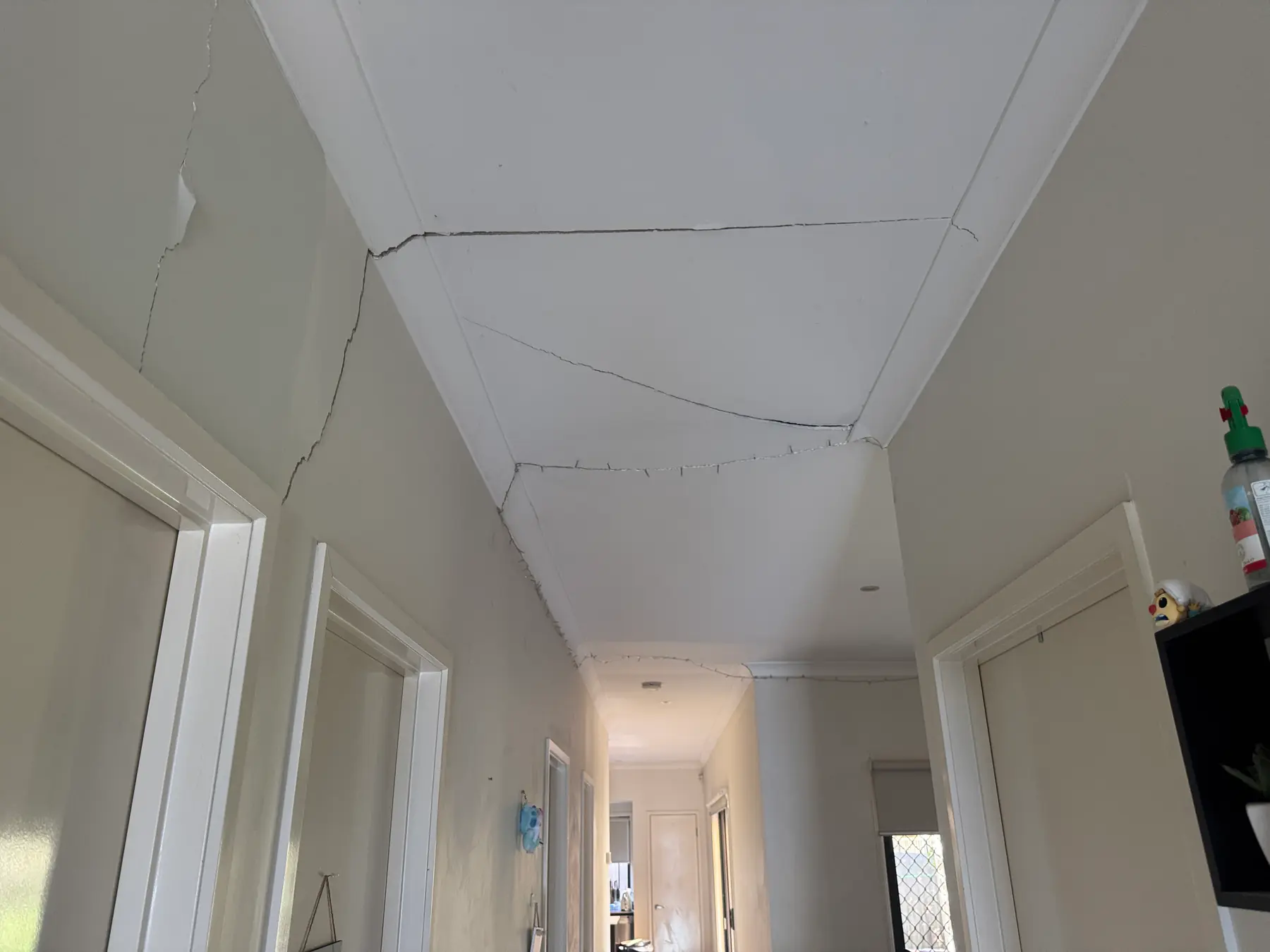 Cracking across a hallway ceiling and adjoining walls.