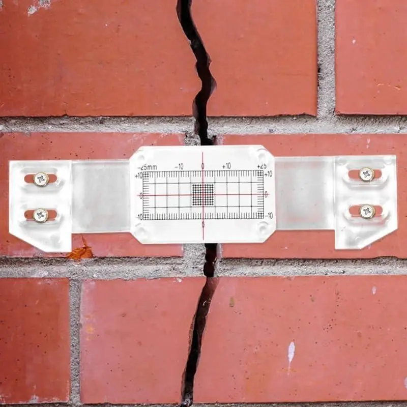 A plastic crack-monitoring gauge spanning a masonry crack.